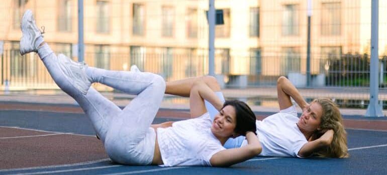 two women doing abs exercises outside