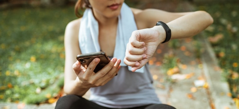 A woman using a smartwatch and a phone during a workout