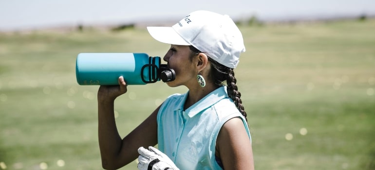 A woman drinking water from a reusable bottle