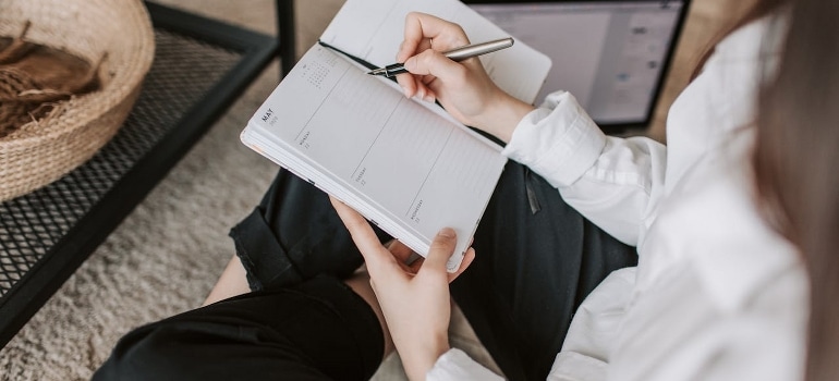 A woman writing in a notebook at home.