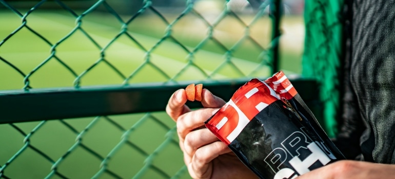 A person near the green fence holding the best supplements to gain muscle.