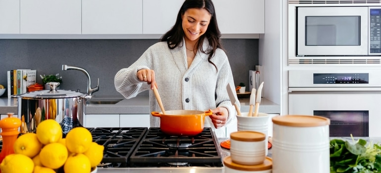 A happy woman is cooking according to volume eating diet in a kitchen. 