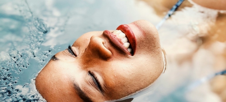 A floating woman on a body of water, practicing cold immersion therapy.