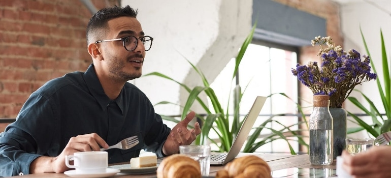 A man is having breakfast in front of the laptop.