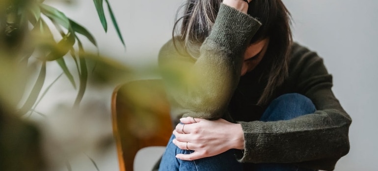 Upset woman embracing knees while sitting on the chair.
