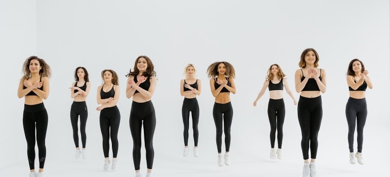 A group of women in black sportswear doing jumping exercises.