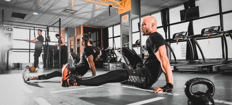 Men working out in a gym and talking about the power of group exercise to combat anxiety.