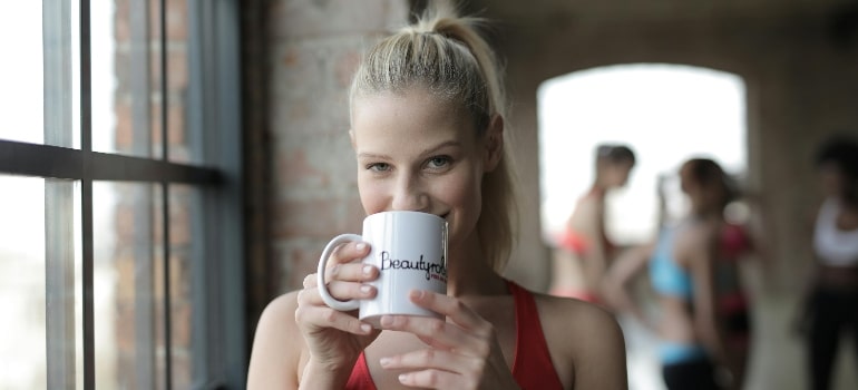 a woman drinking out of a white cup thinking about the benefits of electrolytes