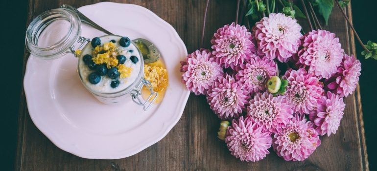 yoghurt and berries in the table next to the pink flowers