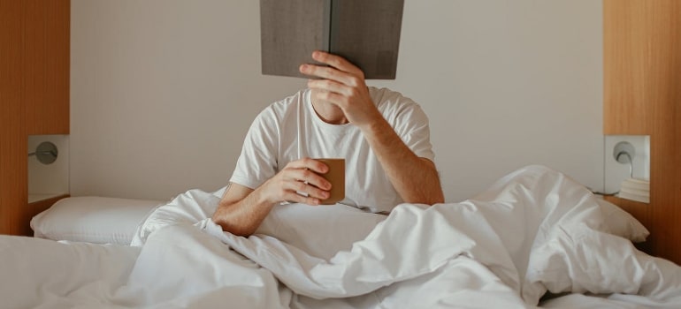 A man is reading a book in bed about ways to increase testosterone levels naturally. 