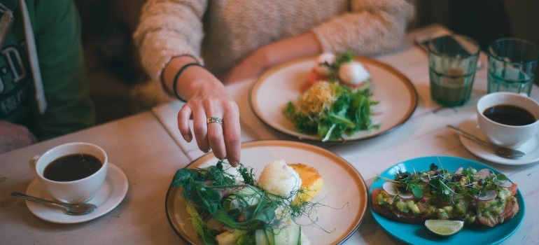 A woman is having a meal with healthy food and coffee. 