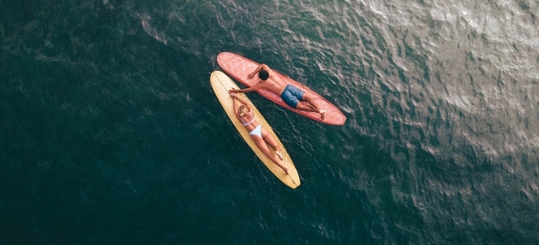 Aerial view of a couple lying on their surfboards while enjoying one of the healthy date ideas in Dubai.