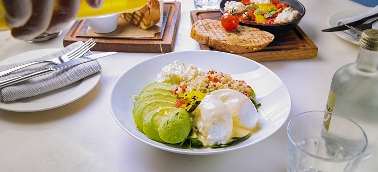 A person pouring dressing on food in one of the top romantic healthy dining spots in Dubai. 