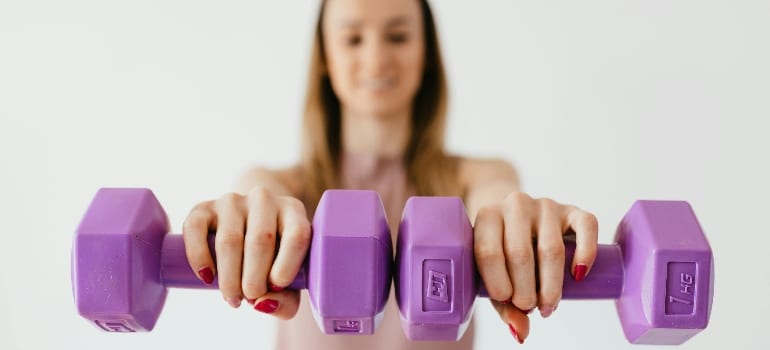 A person training with light dumbbells, which is important while getting back to exercise after plastic surgery
