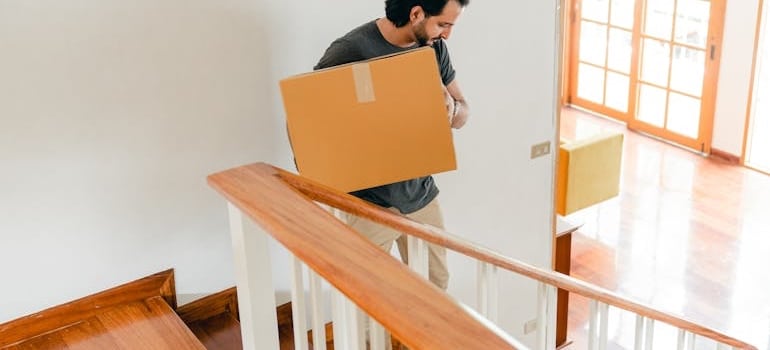 A person carrying a box, which is one of the things that can make staying fit while moving in Dubai possible