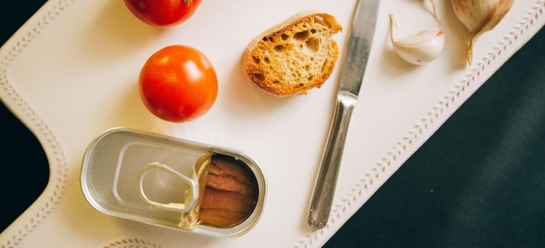 A piece of bread with a can of tuna on a cutting board.