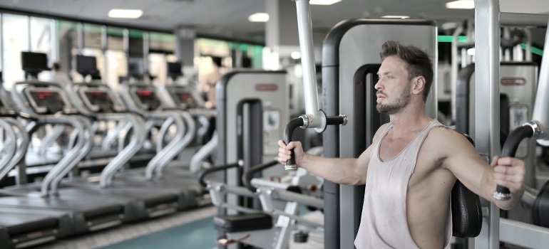 A man holding exercise equipment in a gym and thinking of the inner chest myth. 