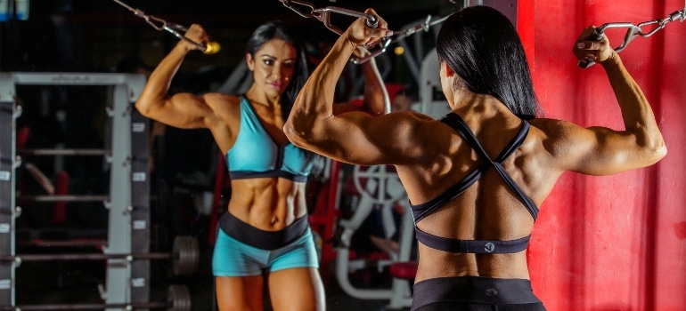 A woman checking herself out at the gym and wondering does Omega 3 help build muscle.