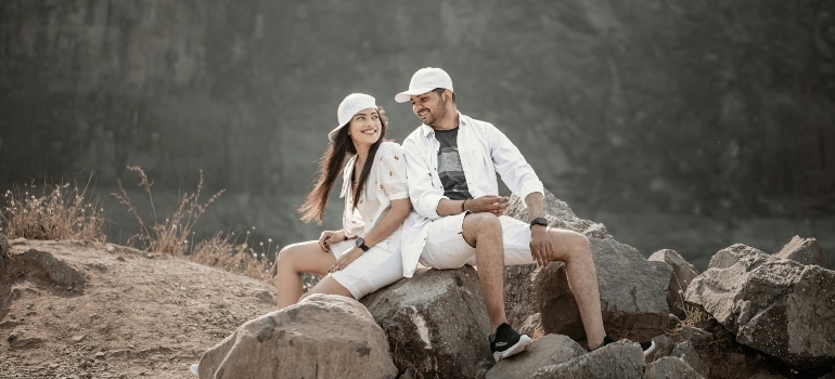 Smiling couple sitting on a rock and thinking about best places for couples to hike.
