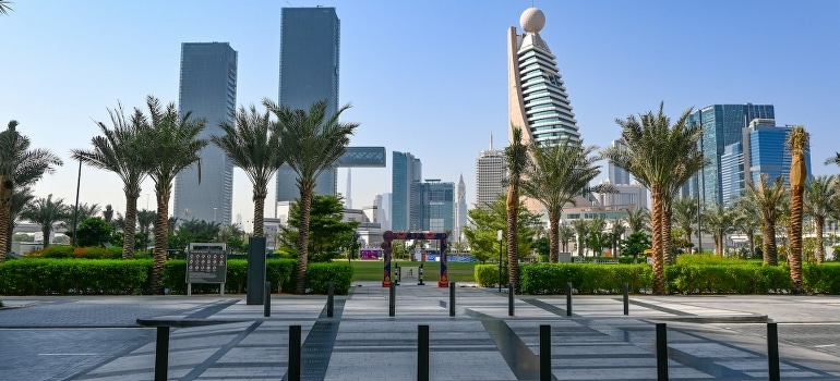 A walkway with palm trees and buildings behind.