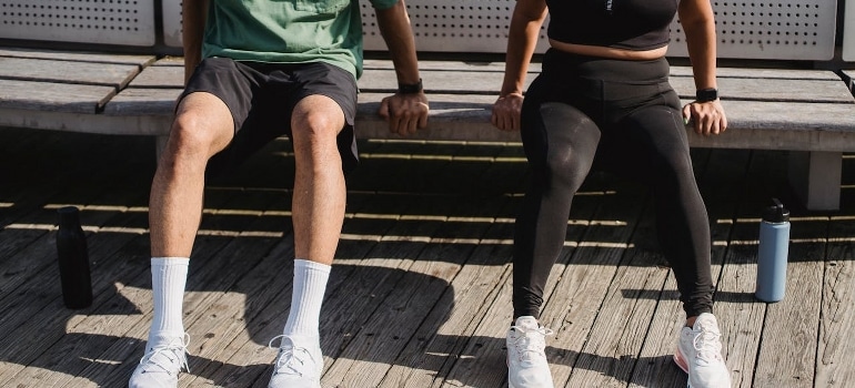 A couple is exercising on the bench outdoors, and they are doing partner workouts at parks in Dubai.