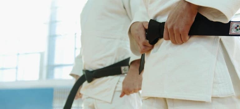 Karate fighter tightening his black belt.