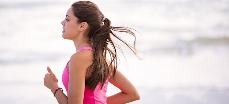 A woman in a pink top running.