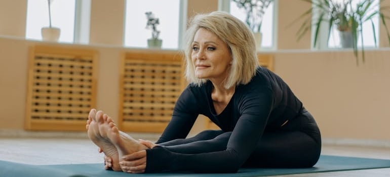 An older woman stretching her lower back and hamstrings.