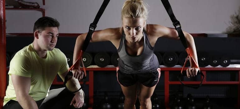 A woman exercising next to her personal trainer to stay fit and healthy after moving
