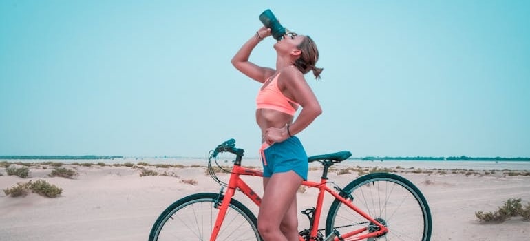 A woman drinking water while riding a bike.