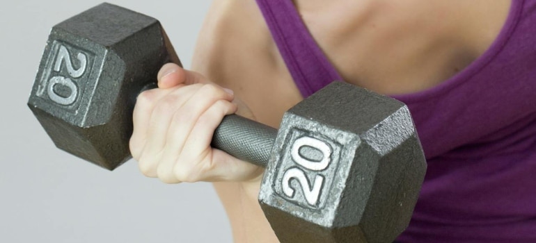 Person lifting a dumbbell as part of an arm workout for busy people