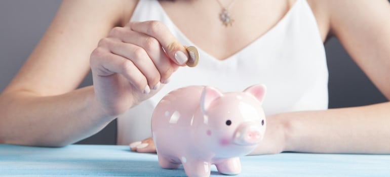 Person putting a coin into a piggy bank