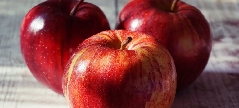 Three red apples on a table can be a good source of the advantages of sugar