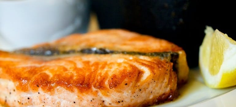 Cooked fish and a lemon slice on a plate