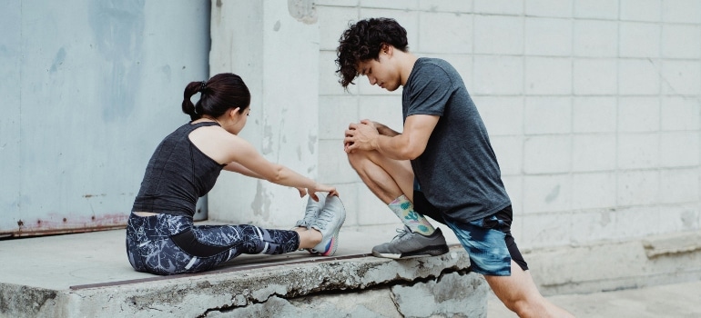 Man and woman performing stretches demonstrating the science of warm-ups to start workouts prepared.