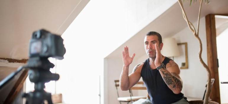 A man is doing exercises in front of the camera, thinking about the pros and cons of joining a personal trainer platform.
