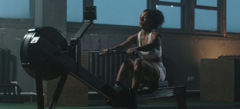 A woman rowing indoors while keeping a steady rhythm during her workout.