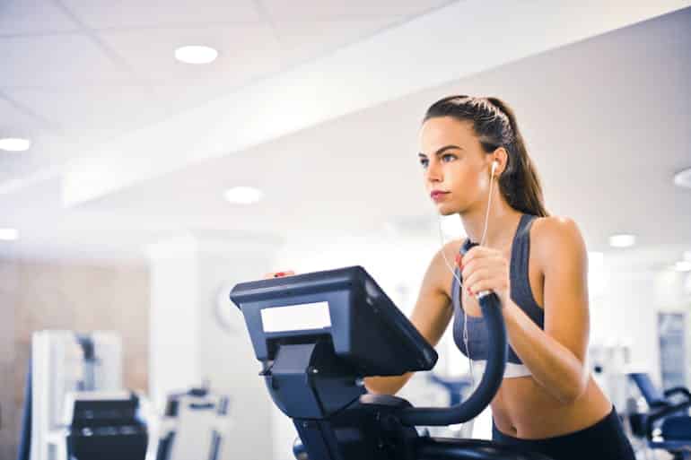 A young female athlete trains alone on a treadmill in a modern gym, highlighting how proper warm-downs improve long-term performance after cardio sessions.