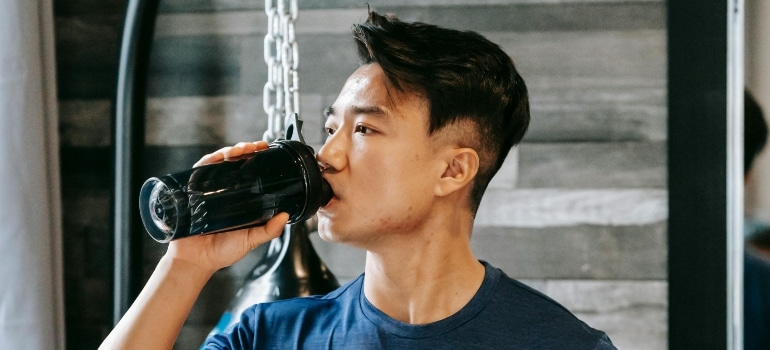 Man drinking water to stay hydrated, supporting muscle recovery and overall health during rest days.